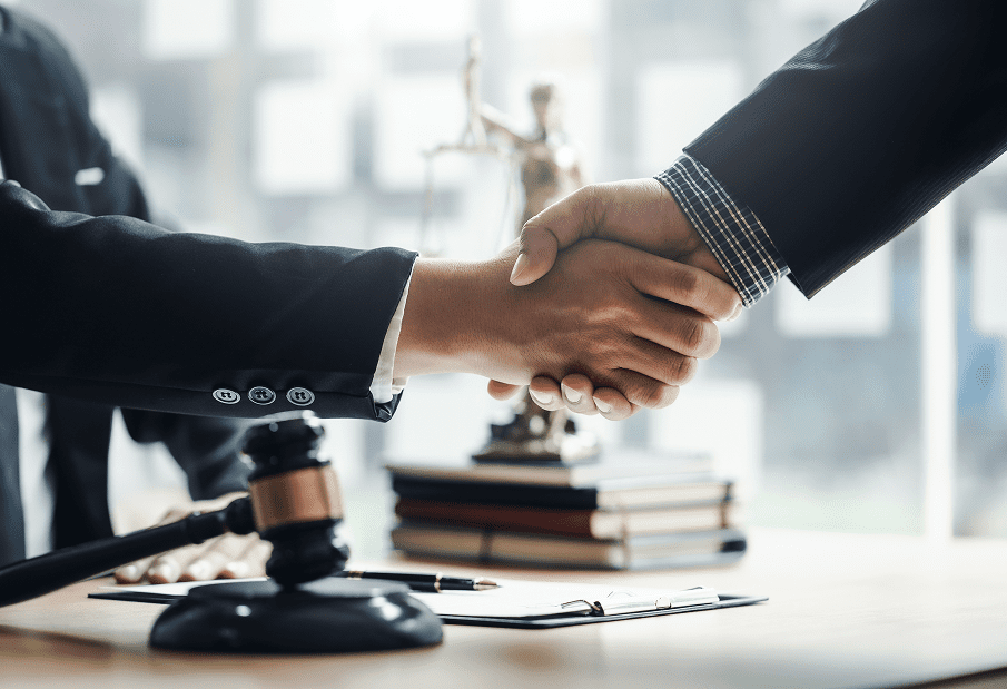 Two professionals shaking hands over a legal agreement.
